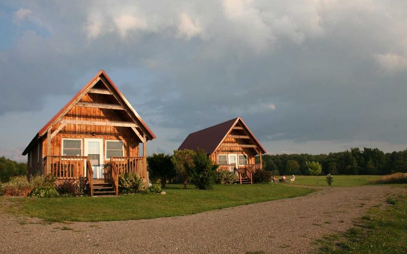 Front of cabins during a summer dusk with visitors relaxing by campfire